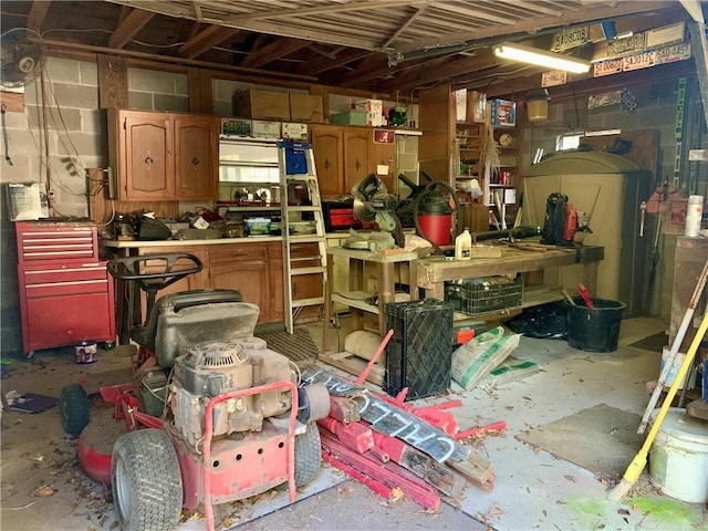 misc room with a workshop area, unfinished concrete flooring, and concrete block wall