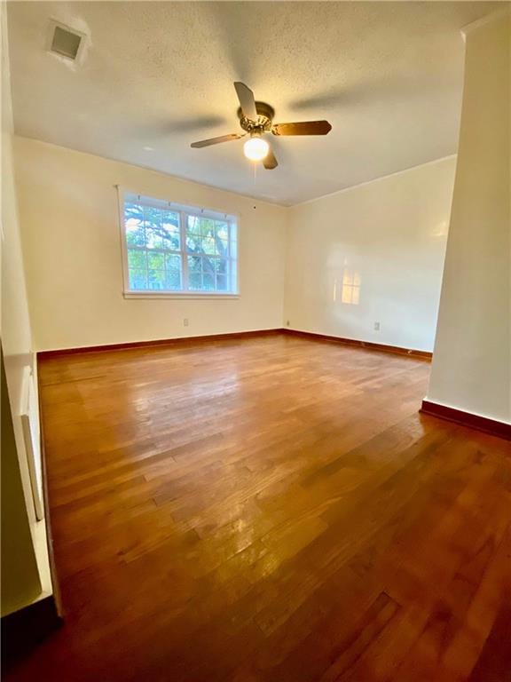 spare room with dark hardwood / wood-style flooring, ceiling fan, and a textured ceiling