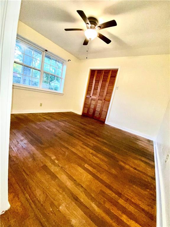 unfurnished bedroom with ceiling fan, a closet, and dark wood-type flooring