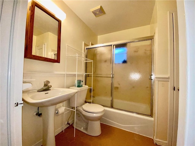 full bathroom with sink, tile floors, toilet, and bath / shower combo with glass door