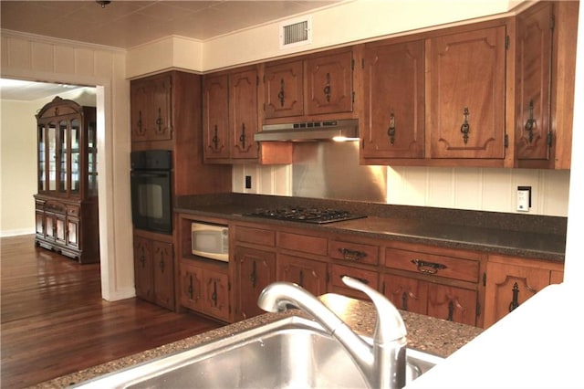 kitchen featuring gas stovetop, dark wood-type flooring, black oven, sink, and ornamental molding