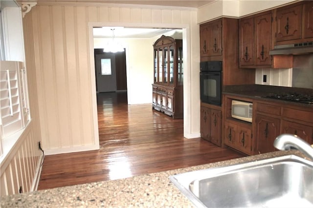 kitchen with sink, light stone counters, dark hardwood / wood-style floors, and black appliances