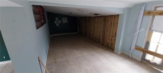 hall featuring wooden walls and vaulted ceiling