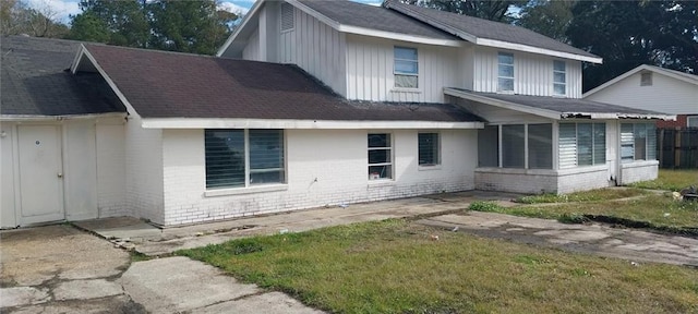 view of side of property with a sunroom and a lawn