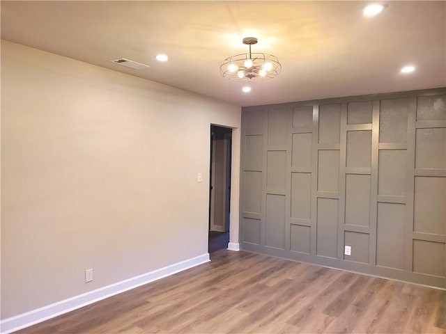 unfurnished room with hardwood / wood-style floors and an inviting chandelier