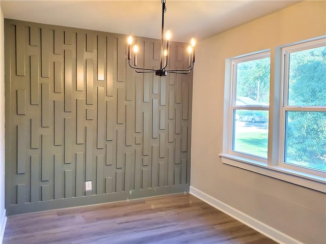 unfurnished dining area featuring hardwood / wood-style floors and a notable chandelier