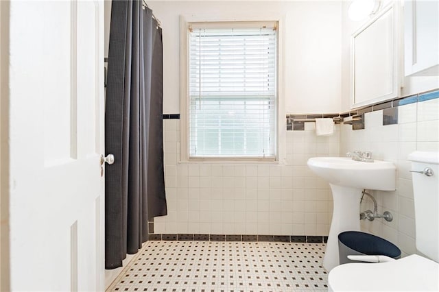 bathroom with tile patterned flooring, toilet, and tile walls