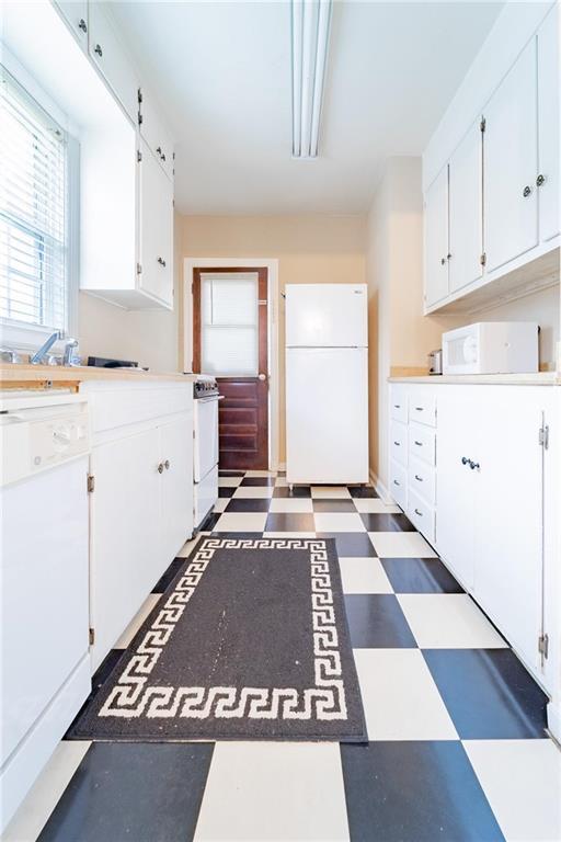 kitchen featuring white cabinetry and white appliances