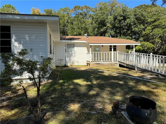 rear view of house featuring a yard and a shingled roof