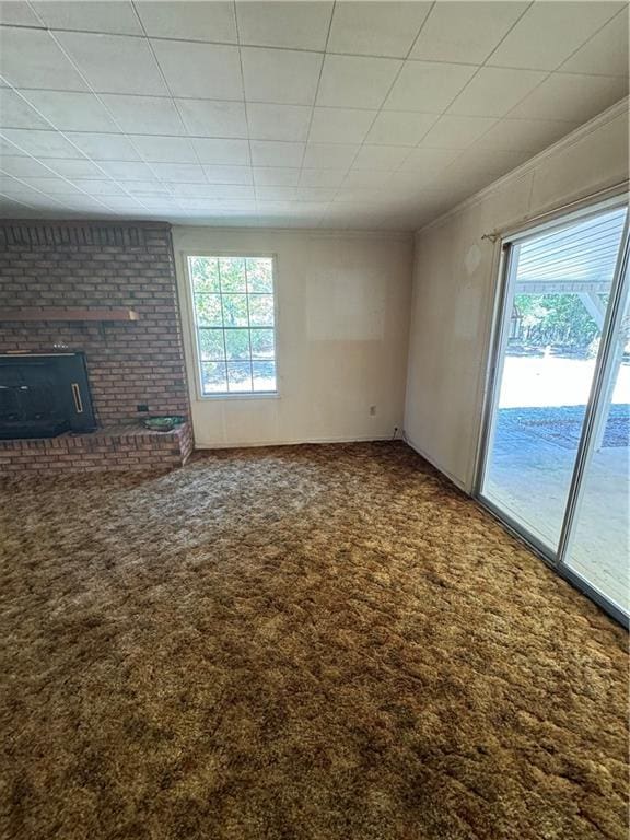 unfurnished living room featuring a fireplace, crown molding, and carpet