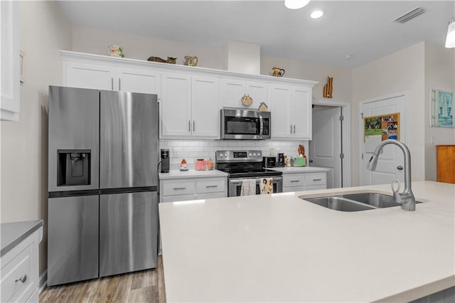 908 Longfellow Pl, Dauphin Island, AL 36528 - kitchen with appliances with stainless steel finishes, a sink, white cabinets, decorative backsplash, and an island with sink