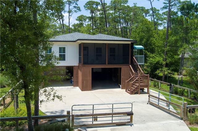 908 Longfellow Pl, Dauphin Island, AL 36528 - back of house featuring driveway, a sunroom, stairs, an attached garage, and roof with shingles