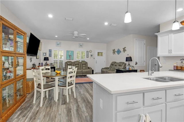 908 Longfellow Pl, Dauphin Island, AL 36528 - kitchen featuring a sink, a ceiling fan, light wood-style floors, light countertops, and white cabinetry