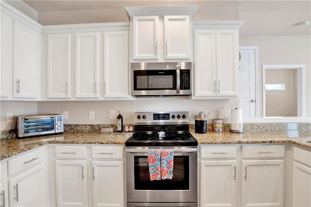 kitchen featuring stainless steel appliances, white cabinetry, and light stone counters