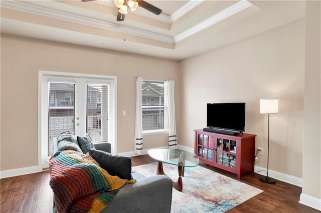 living room featuring dark hardwood / wood-style flooring, a raised ceiling, ceiling fan, and crown molding