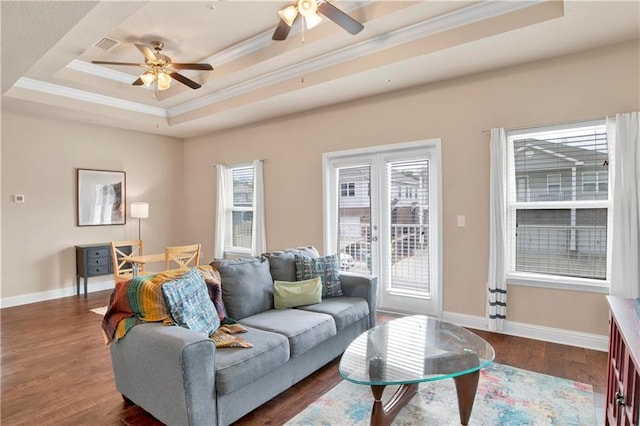 living room featuring dark wood-type flooring, ceiling fan, a tray ceiling, and crown molding