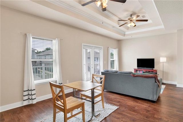 dining space featuring a raised ceiling, a healthy amount of sunlight, and dark wood-type flooring