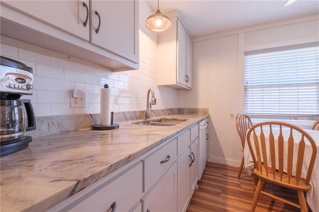 kitchen with white cabinets, sink, tasteful backsplash, light stone counters, and wood-type flooring