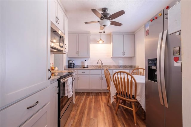 kitchen with ceiling fan, light hardwood / wood-style flooring, decorative light fixtures, white cabinets, and appliances with stainless steel finishes