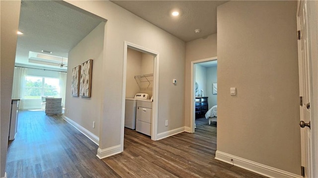 hall featuring a raised ceiling, washing machine and clothes dryer, and dark hardwood / wood-style flooring