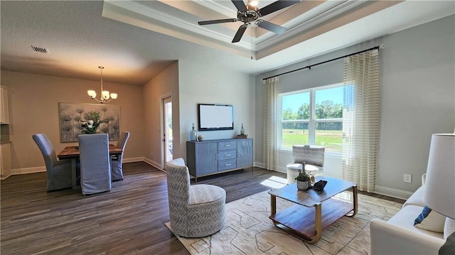 living room with ceiling fan with notable chandelier, hardwood / wood-style flooring, a raised ceiling, crown molding, and a textured ceiling