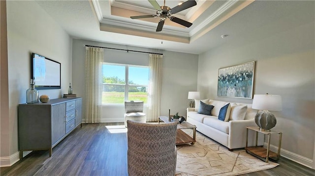 living room featuring a raised ceiling, ornamental molding, hardwood / wood-style floors, and ceiling fan