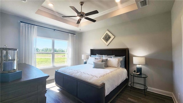 bedroom with a raised ceiling, ceiling fan, crown molding, and dark hardwood / wood-style flooring