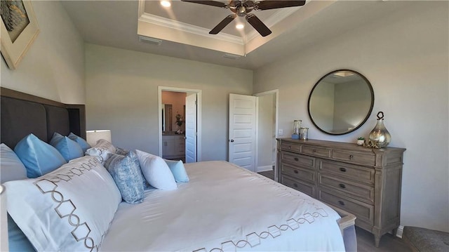 bedroom featuring a raised ceiling, ornamental molding, ensuite bathroom, and ceiling fan