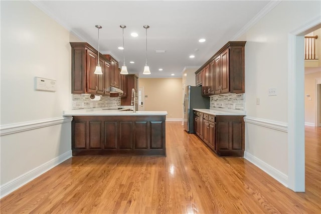 kitchen featuring kitchen peninsula, stainless steel fridge, light hardwood / wood-style flooring, tasteful backsplash, and decorative light fixtures