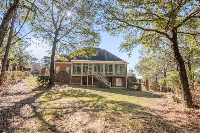 rear view of house with a yard and a sunroom