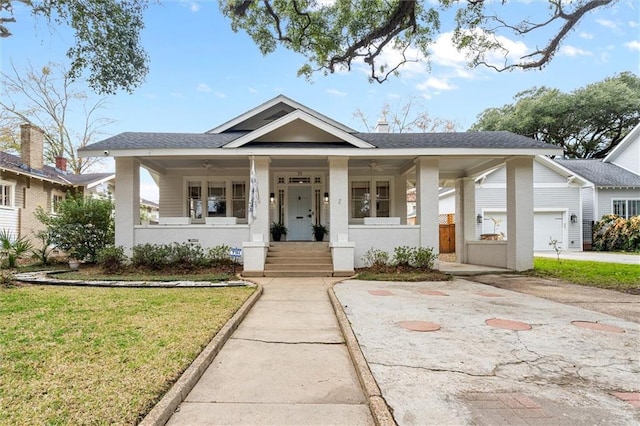 bungalow-style home with a garage, covered porch, and a front lawn