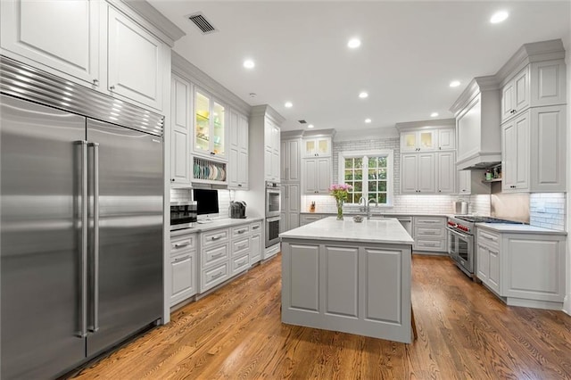4008 Mcgregor Oaks, Mobile, AL 36608 - kitchen featuring high end appliances, light countertops, decorative backsplash, a center island, and wood finished floors