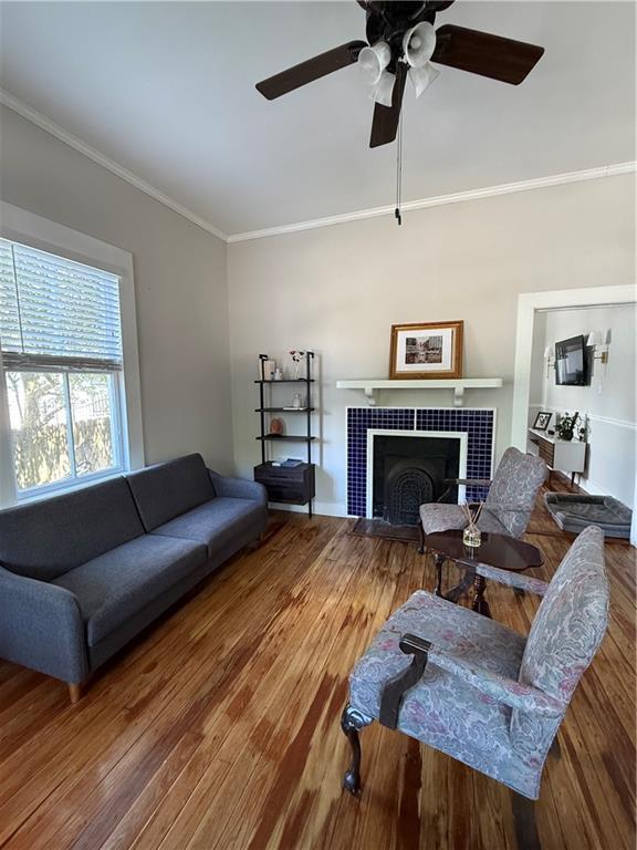 1367 Brown St, Mobile, AL 36604 - living area with ornamental molding, a tiled fireplace, wood finished floors, and a ceiling fan