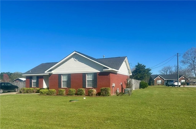 view of home's exterior featuring fence, a yard, central AC unit, and brick siding