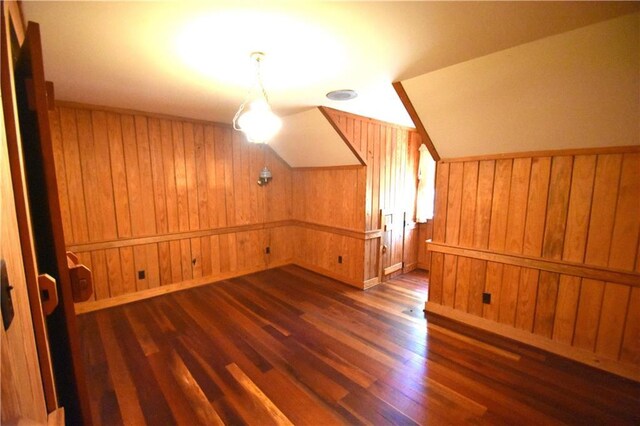 unfurnished living room featuring beam ceiling, a fireplace, wooden walls, and wood finished floors