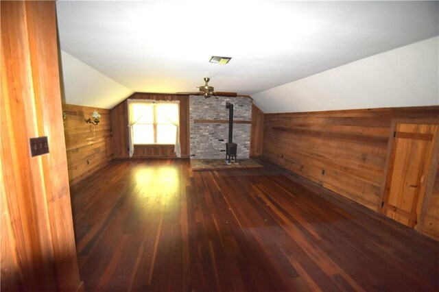 unfurnished living room with a fireplace, wooden walls, beamed ceiling, and wood finished floors