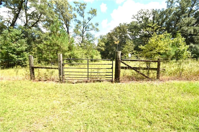 view of gate with a yard and fence