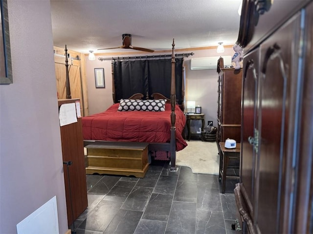 bedroom featuring a wall mounted AC, a textured ceiling, and a barn door