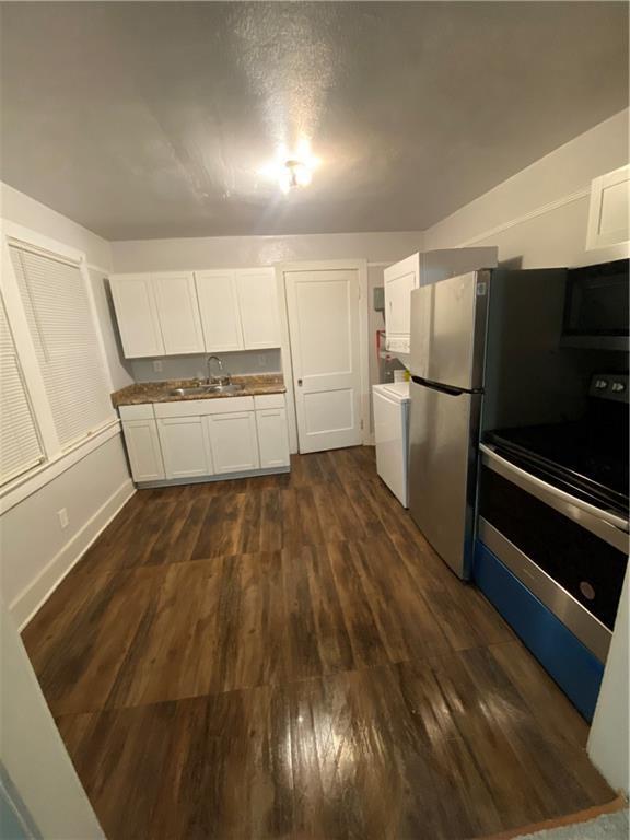 kitchen featuring dark hardwood / wood-style floors, washer / dryer, sink, white cabinetry, and range