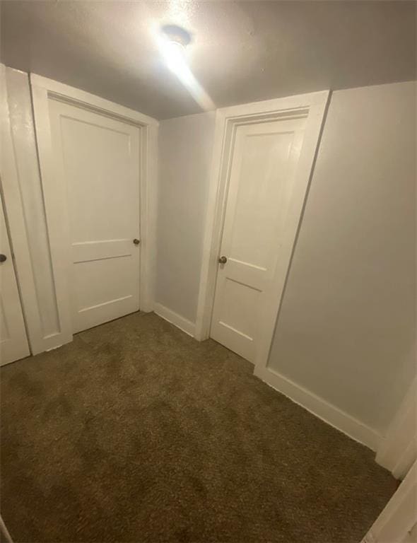 hall with dark colored carpet