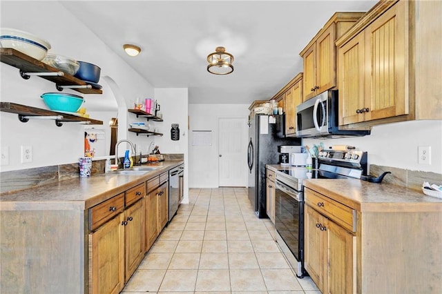 kitchen featuring arched walkways, light tile patterned floors, open shelves, appliances with stainless steel finishes, and a sink