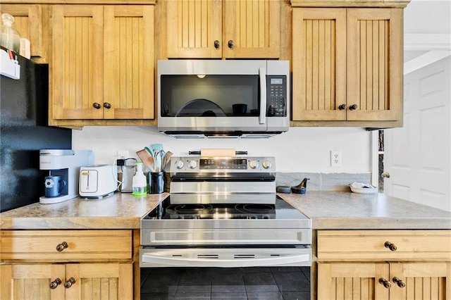 kitchen featuring stainless steel appliances, light countertops, and light brown cabinetry