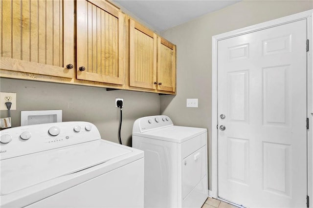 laundry room featuring light tile patterned floors, washing machine and dryer, and cabinet space