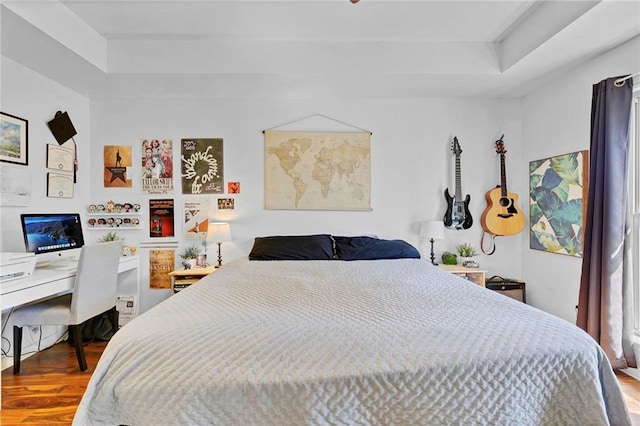 bedroom with a tray ceiling and wood finished floors