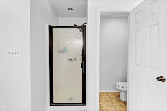 bathroom featuring toilet, a stall shower, tile patterned flooring, and baseboards