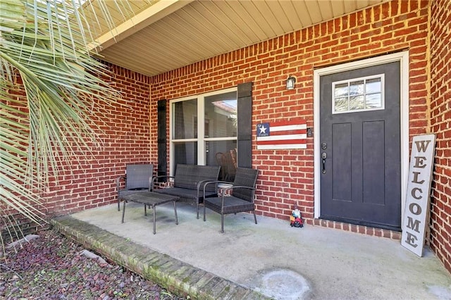 doorway to property featuring covered porch and brick siding