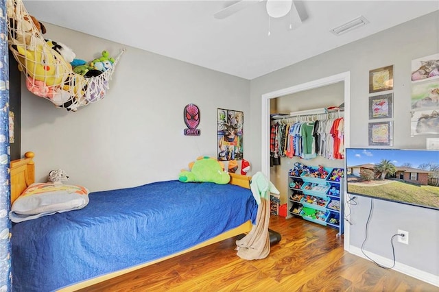 bedroom featuring a closet, wood finished floors, visible vents, and a ceiling fan