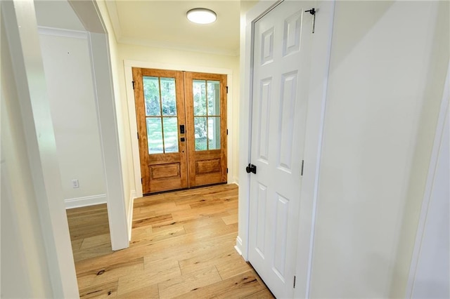 foyer entrance featuring ornamental molding, french doors, and light hardwood / wood-style flooring