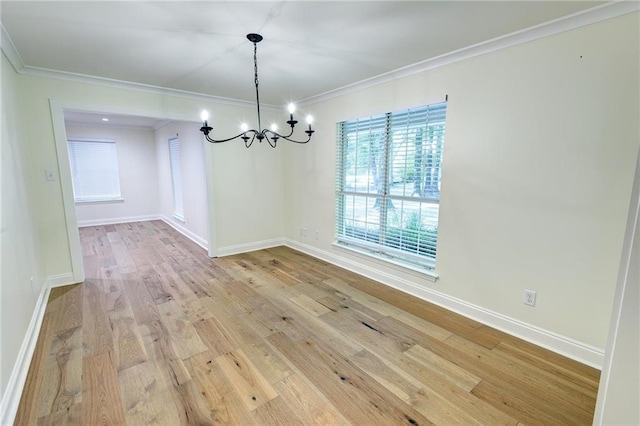 empty room with crown molding, an inviting chandelier, and light hardwood / wood-style flooring