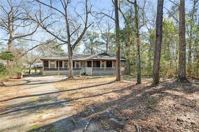 view of front facade featuring dirt driveway and a porch